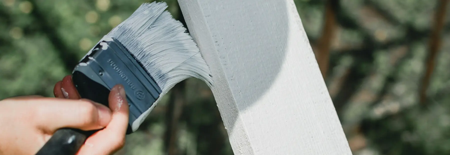 Penseel met witte verf op een pas geschilderde houten plank